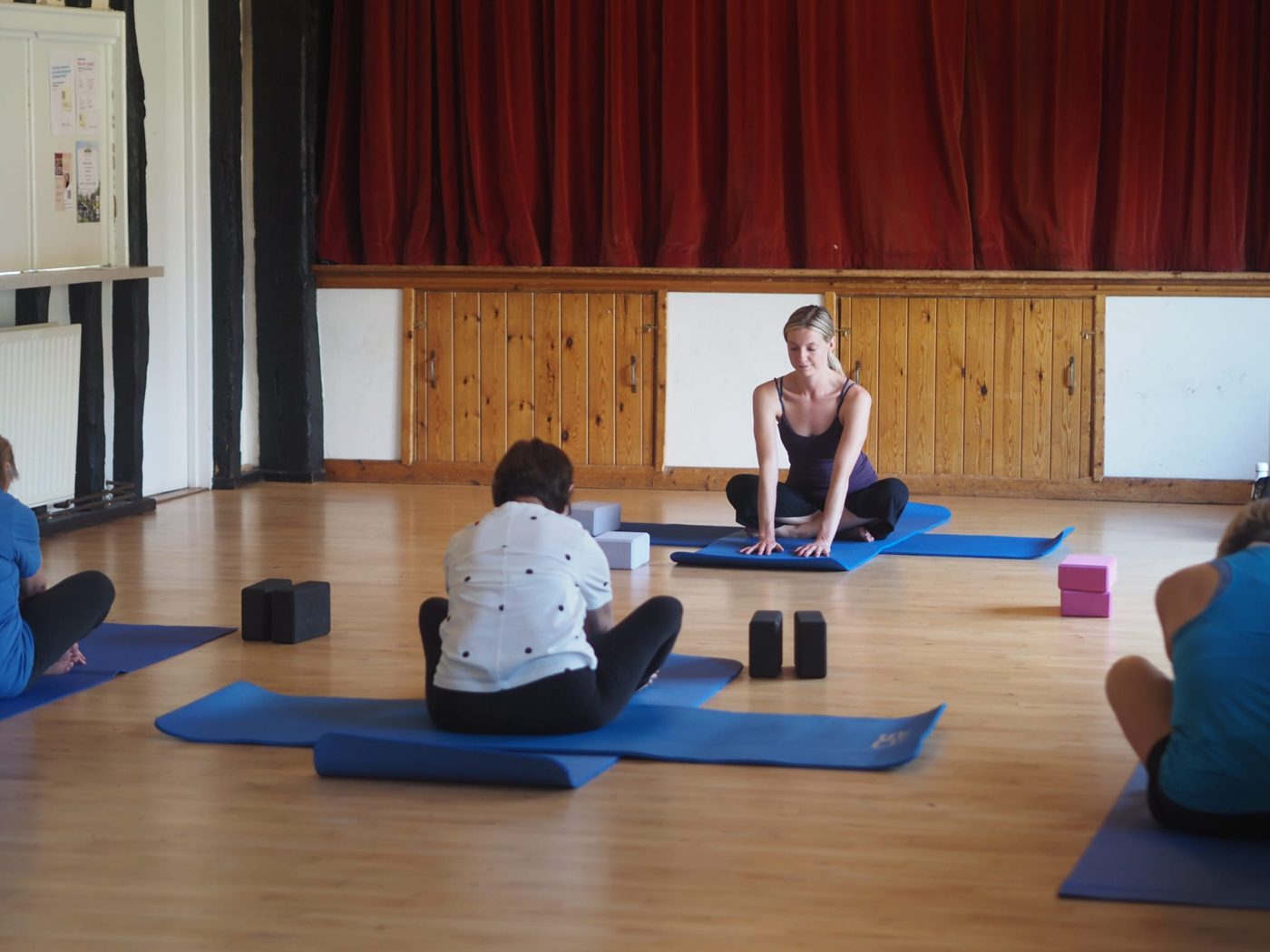 Tallulah teaching a seated stretch in a village hall