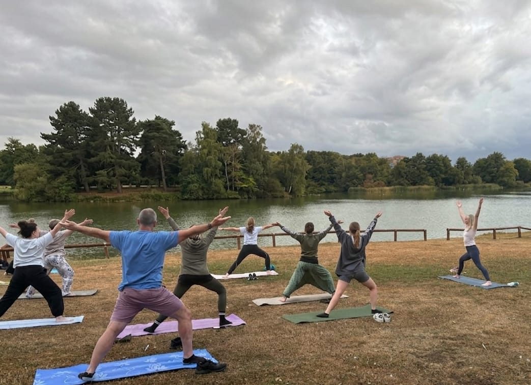 An outdoor group yoga class beside a lake